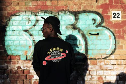 Streetwear Trends 2023. Man Standing In Front Of A Graffiti Wall.